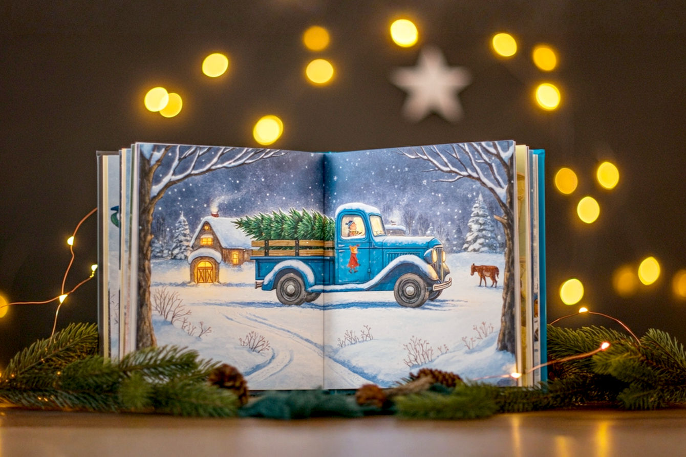 A heartwarming, lifelike professional photograph of an open "Little Blue Truck's Christmas" book, beautifully illustrated pages showing Blue Truck delivering Christmas trees in a snowy, magical farm setting. A soft, warm glow emanates from the book, surrounded by subtle holiday decorations like twinkling fairy lights and natural pine sprigs, creating a cozy and inviting atmosphere. The focus is on the book, slightly open to a key illustration, with a shallow depth of field. Soft, warm lighting emphasizes the festive and gentle mood.