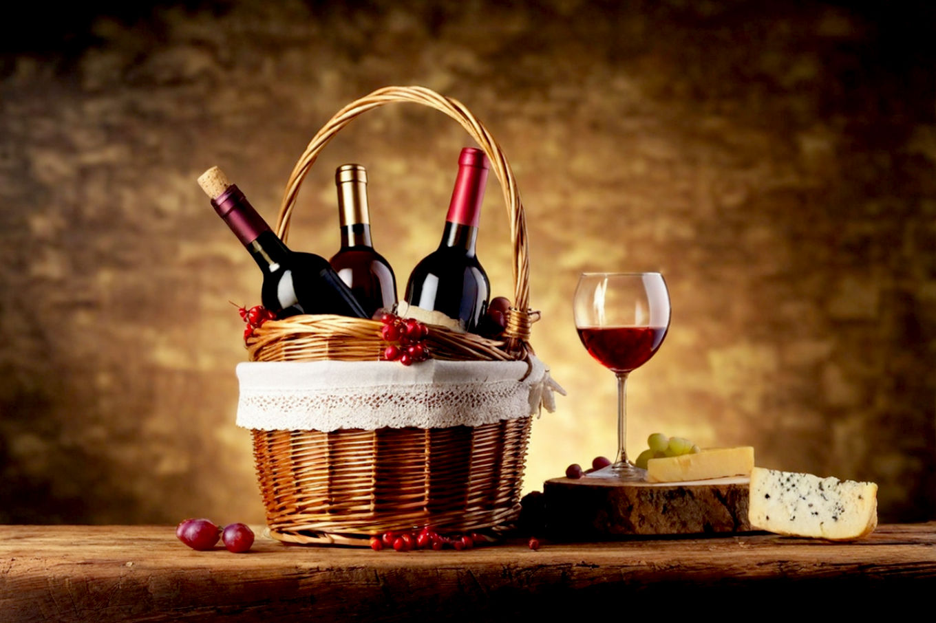 Lifelike pro photography style image: A beautifully arranged, rustic-chic Christmas wine hamper overflowing with a mix of red, white, and sparkling wine bottles. Include gourmet food items like artisanal cheeses, cured meats, dark chocolates, and dried fruits. The hamper should be set against a warm, festive backdrop with soft, inviting lighting, perhaps with subtle hints of pine branches, twinkling fairy lights, and a cozy fireplace in the blurred background. Focus on rich textures, deep colors, and an overall luxurious, inviting atmosphere. Shot with a shallow depth of field to highlight the hamper.