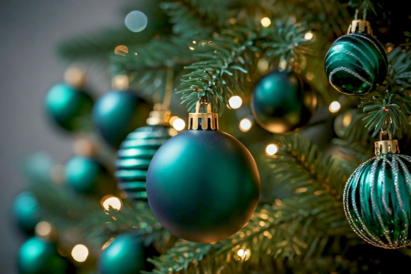 A professional, lifelike photograph of a beautifully decorated Christmas tree, prominently featuring deep emerald green and forest green glass and matte ornaments. The tree is lit with warm, soft white lights, casting a gentle glow. Gold and subtle silver accents are interspersed among the green ornaments. The composition is a close-up, slightly blurred shot of a section of the tree, focusing on the rich textures and reflective qualities of the green ornaments. The background is softly out of focus, suggesting a cozy, elegant living room. The mood is warm, inviting, and sophisticated. Pro photography style, high resolution, natural light, shallow depth of field.