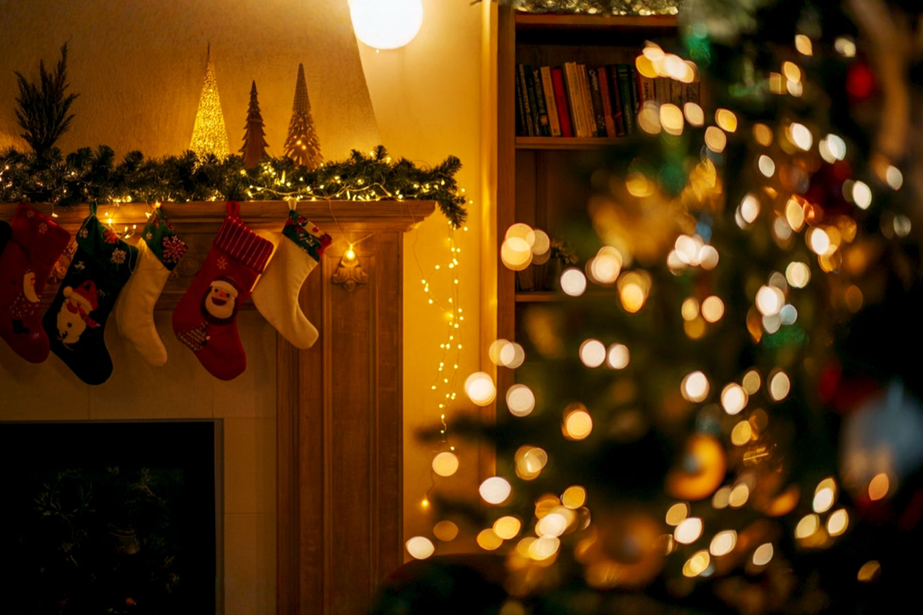 A warm, inviting living room scene during the holiday season. The room is beautifully decorated with a Christmas tree adorned with soft, warm white LED lights that glow gently. Fairy lights are delicately draped over a mantelpiece with festive garlands, and subtle string lights are woven into a bookshelf in the background. The lighting is cozy and ambient, casting a soft, golden glow on comfortable furniture. There are no people visible, focusing solely on the beautifully lit interior. The composition is a medium shot, capturing the depth and warmth of the decorated space. Professional photography style, high resolution, lifelike, with a shallow depth of field to emphasize the lights. The mood is peaceful, magical, and festive.