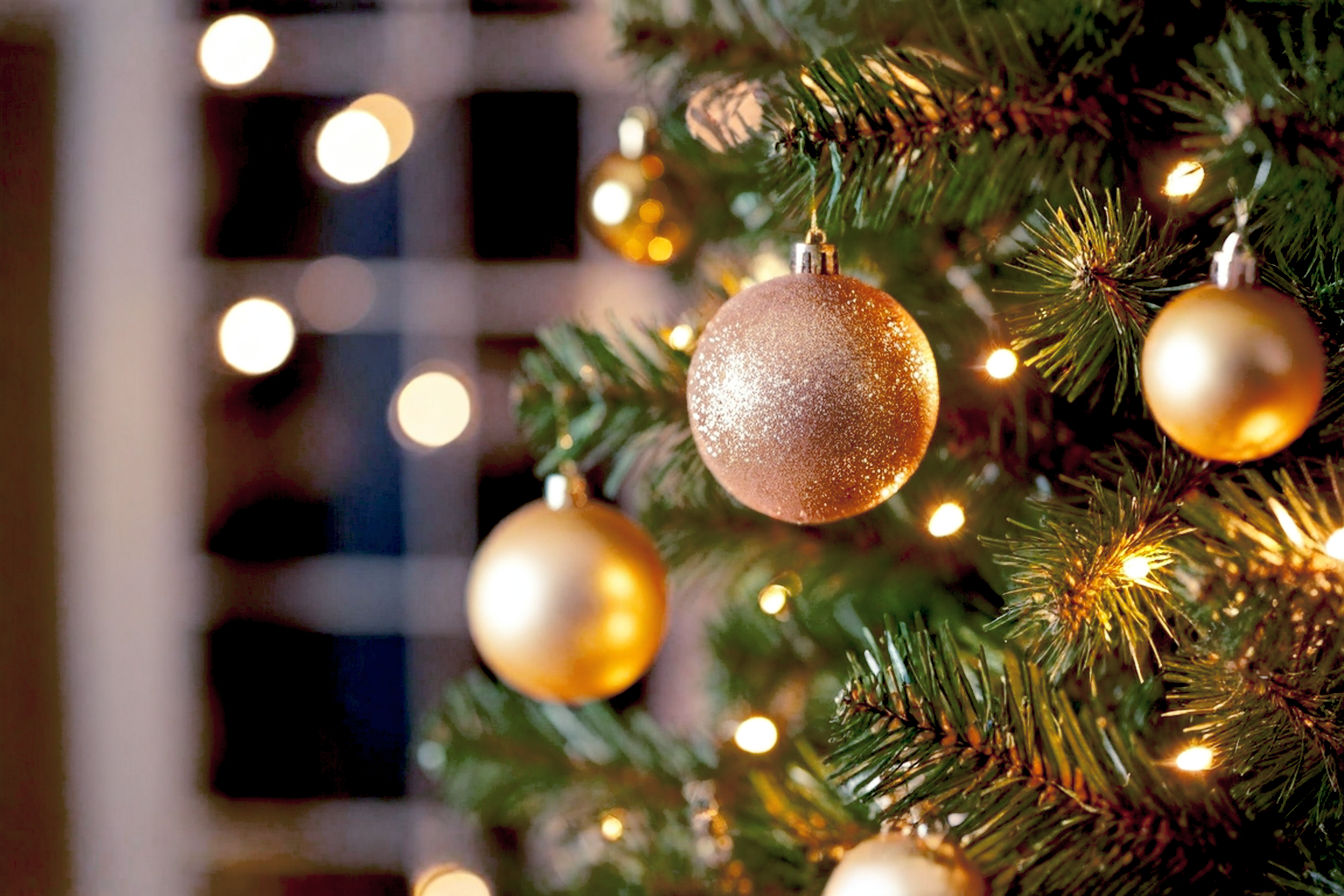 Professional, lifelike, high-resolution photograph of a meticulously decorated Christmas tree, showcasing a blend of unique, non-traditional ornaments and lighting. The tree is centered, well-lit with soft, warm ambient light, emphasizing the intricate details and textures of the decorations. The background is softly blurred (bokeh effect) to keep the focus on the tree, suggesting a cozy, inviting home interior. The overall mood is festive, sophisticated, and inspiring, highlighting the core theme of creative, personalized holiday decor beyond typical red and green. No people or pets are visible. Shot with a prime lens for shallow depth of field, natural light.